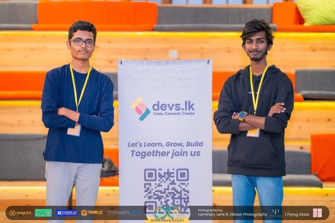 Two Devs.lk volunteers beside the Devs.lk banner at Arduino Day Sri Lanka 2024